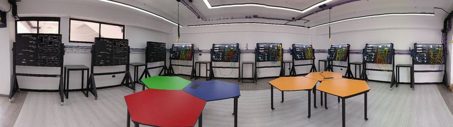 Vista panorámica de un laboratorio de automatización industrial equipado con varios bancos didácticos SYSTRONIC de PLC y neumática
