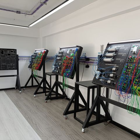 Fila de bancos didácticos de automatización industrial y PLC instalados en un laboratorio universitario